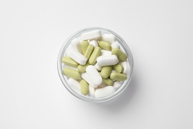 Photo of Different vitamin pills in bowl on white background, top view