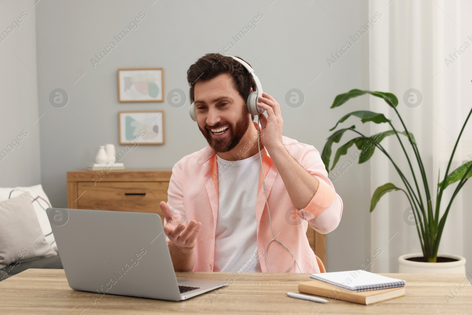 Photo of Man in headphones having video chat via laptop at home