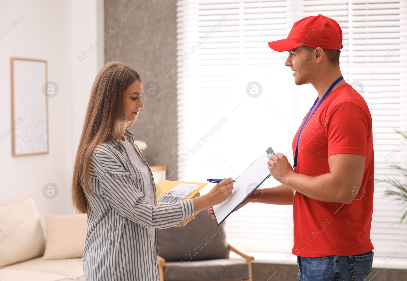 Photo of Woman signing for delivered parcels at home. Courier service