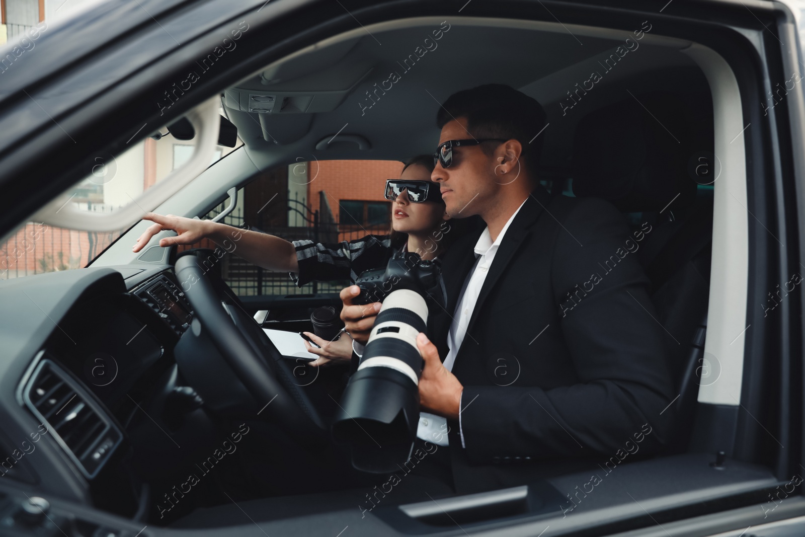 Photo of Private detectives with modern camera spying from car