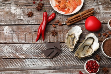 Natural aphrodisiac. Different food products and heart model on wooden table, flat lay. Space for text