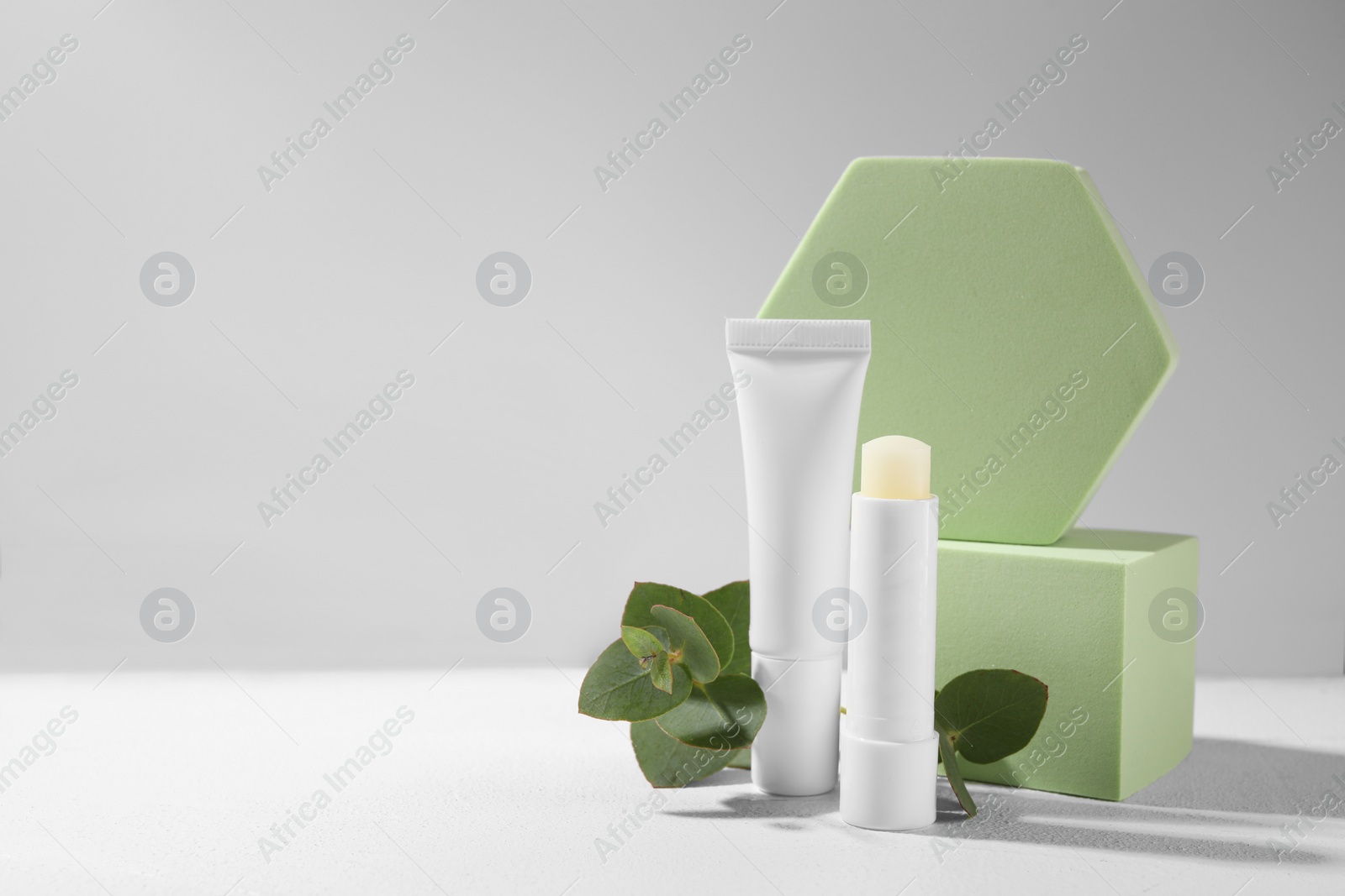 Photo of Stylish presentation of different lip balms on white table, space for text