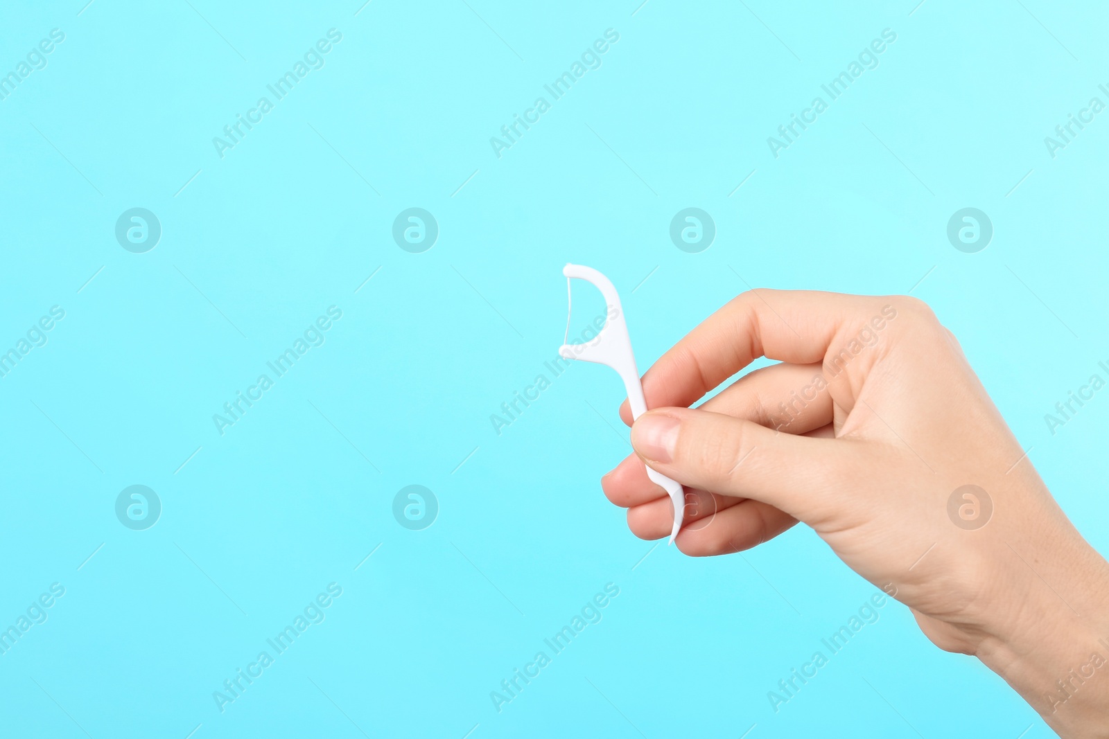 Photo of Woman holding dental floss pick on color background, space for text. Mouth and teeth care