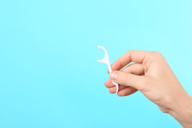 Photo of Woman holding dental floss pick on color background, space for text. Mouth and teeth care