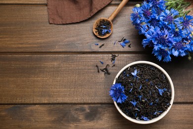 Photo of Composition with dry tea leaves and cornflowers on wooden table, flat lay. Space for text