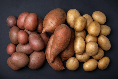 Different types of fresh potatoes on black table, flat lay.