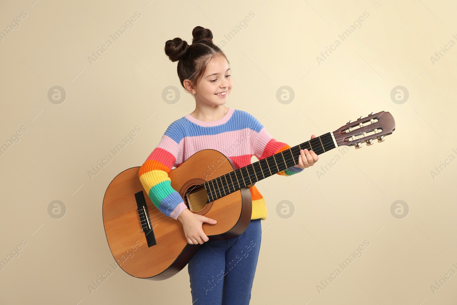 Photo of Cute little girl playing guitar on color background