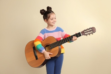 Cute little girl playing guitar on color background