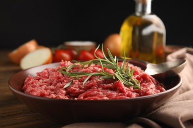 Photo of Fresh minced meat with rosemary on wooden table, closeup