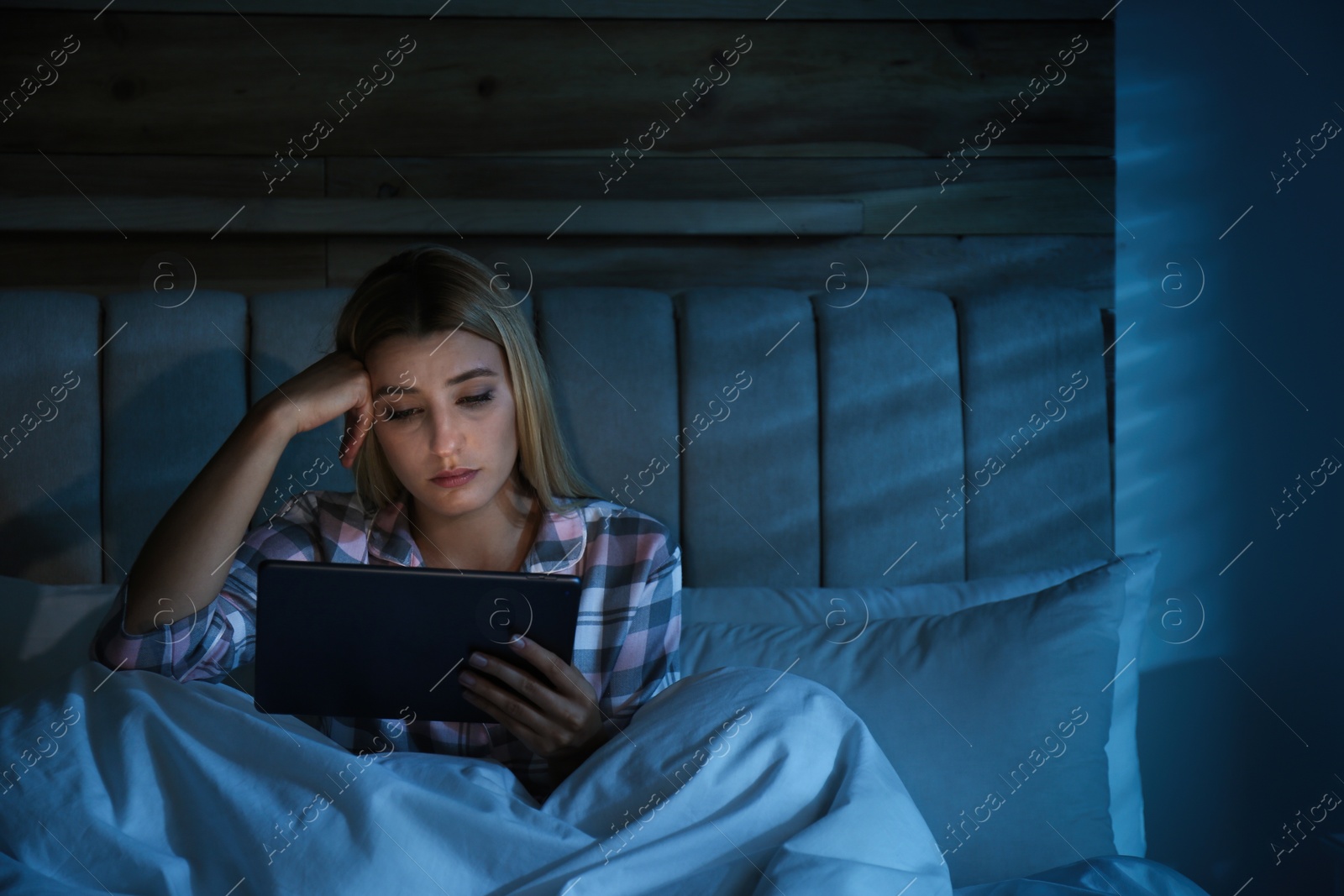 Photo of Young woman using tablet in bed at night. Sleeping disorder problem