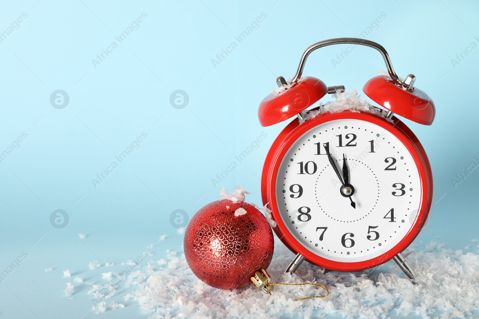 Photo of Alarm clock with Christmas decor on light blue background, space for text. New Year countdown