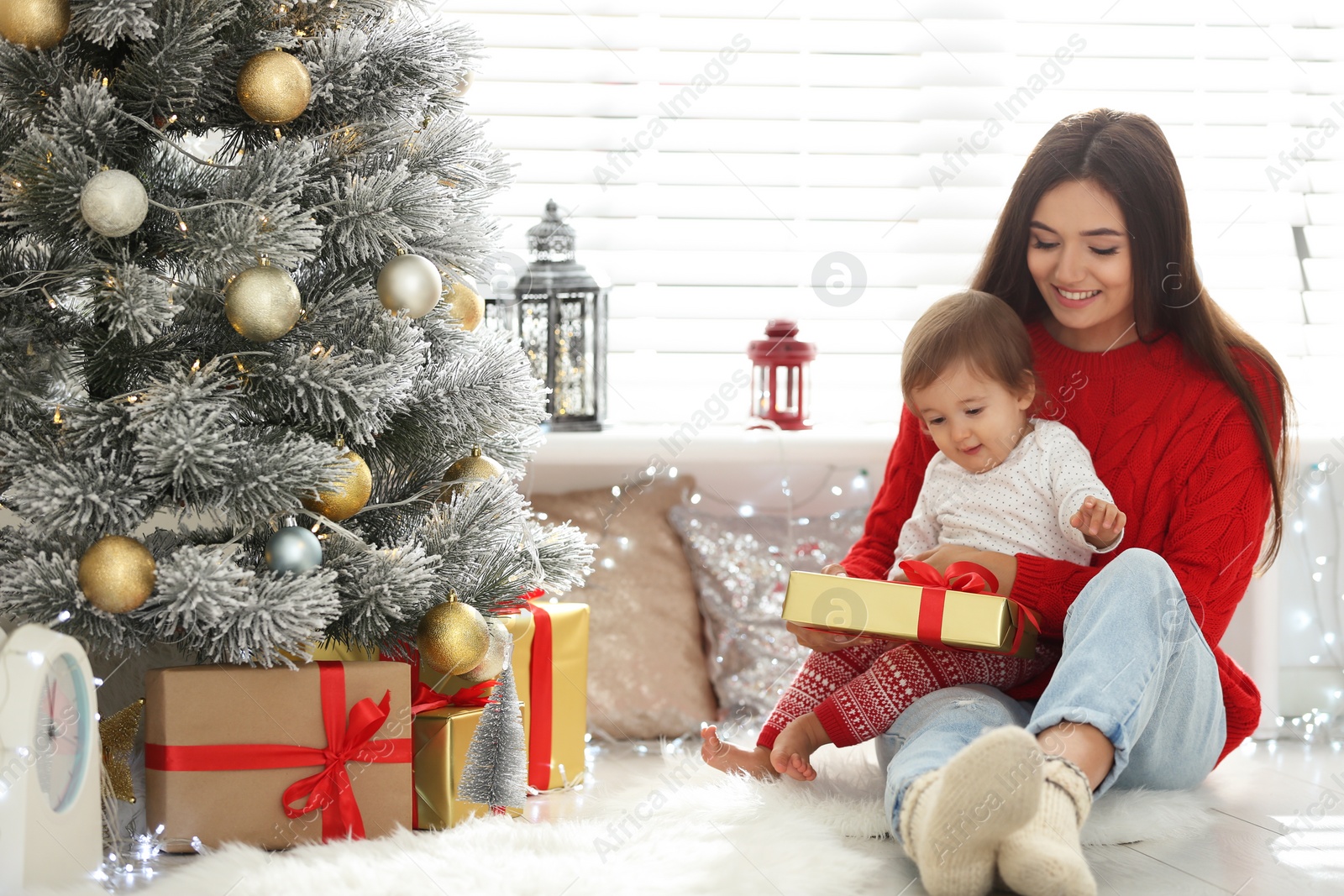 Photo of Mother and her cute baby near Christmas tree at home