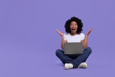 Photo of Emotional young woman using laptop on purple background. Space for text