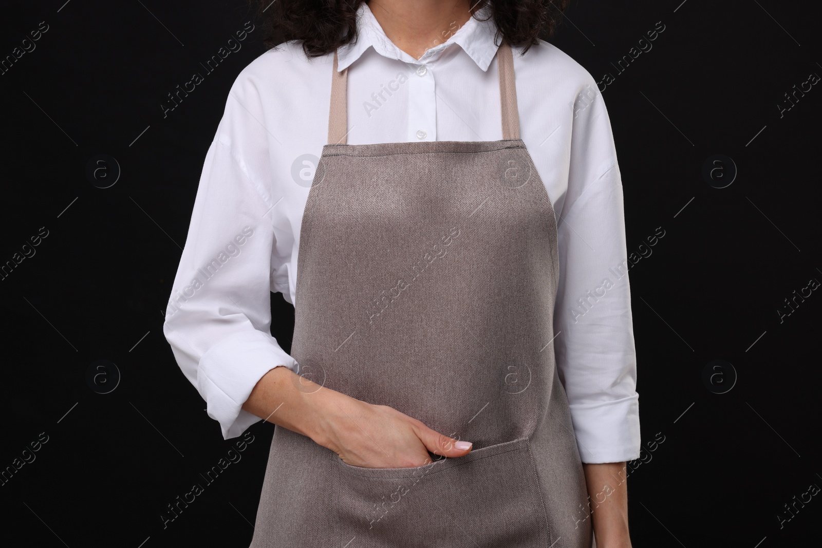 Photo of Woman wearing kitchen apron on black background, closeup. Mockup for design