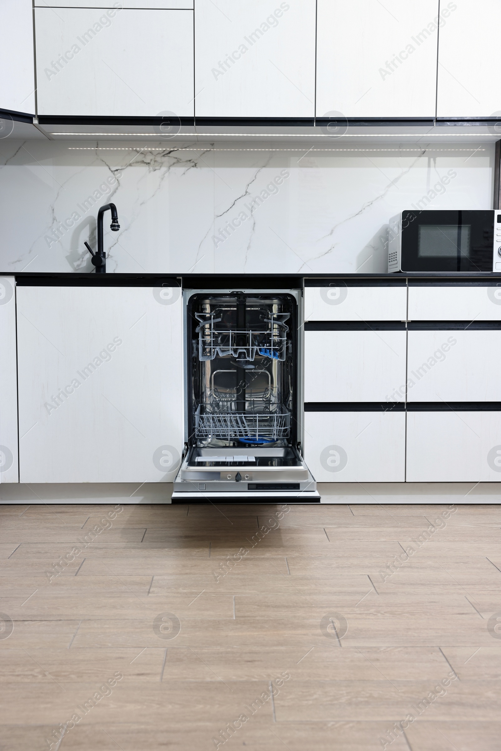 Photo of Open clean empty dishwasher in kitchen. Home appliance