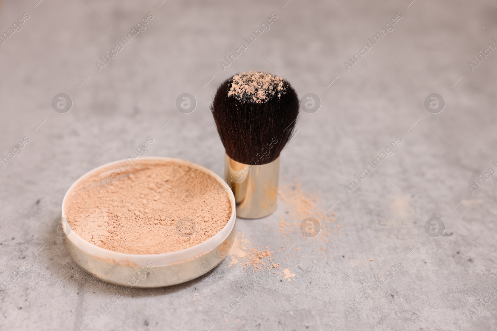 Photo of Face powder and brush on grey textured table, closeup. Space for text