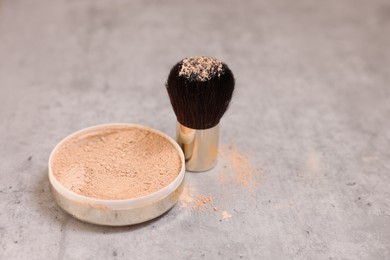 Photo of Face powder and brush on grey textured table, closeup. Space for text