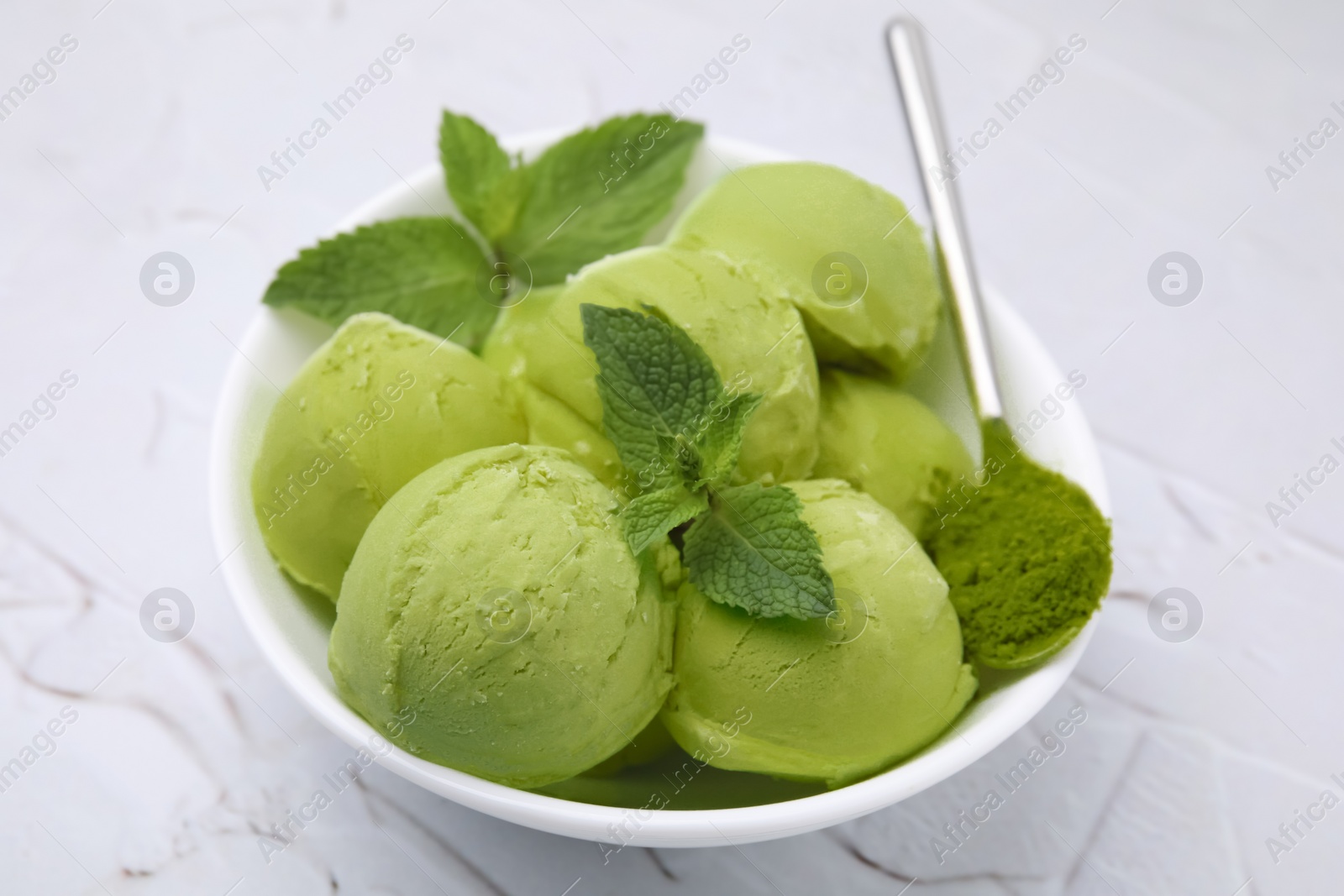 Photo of Tasty matcha ice cream and spoon with powder on white textured table, closeup