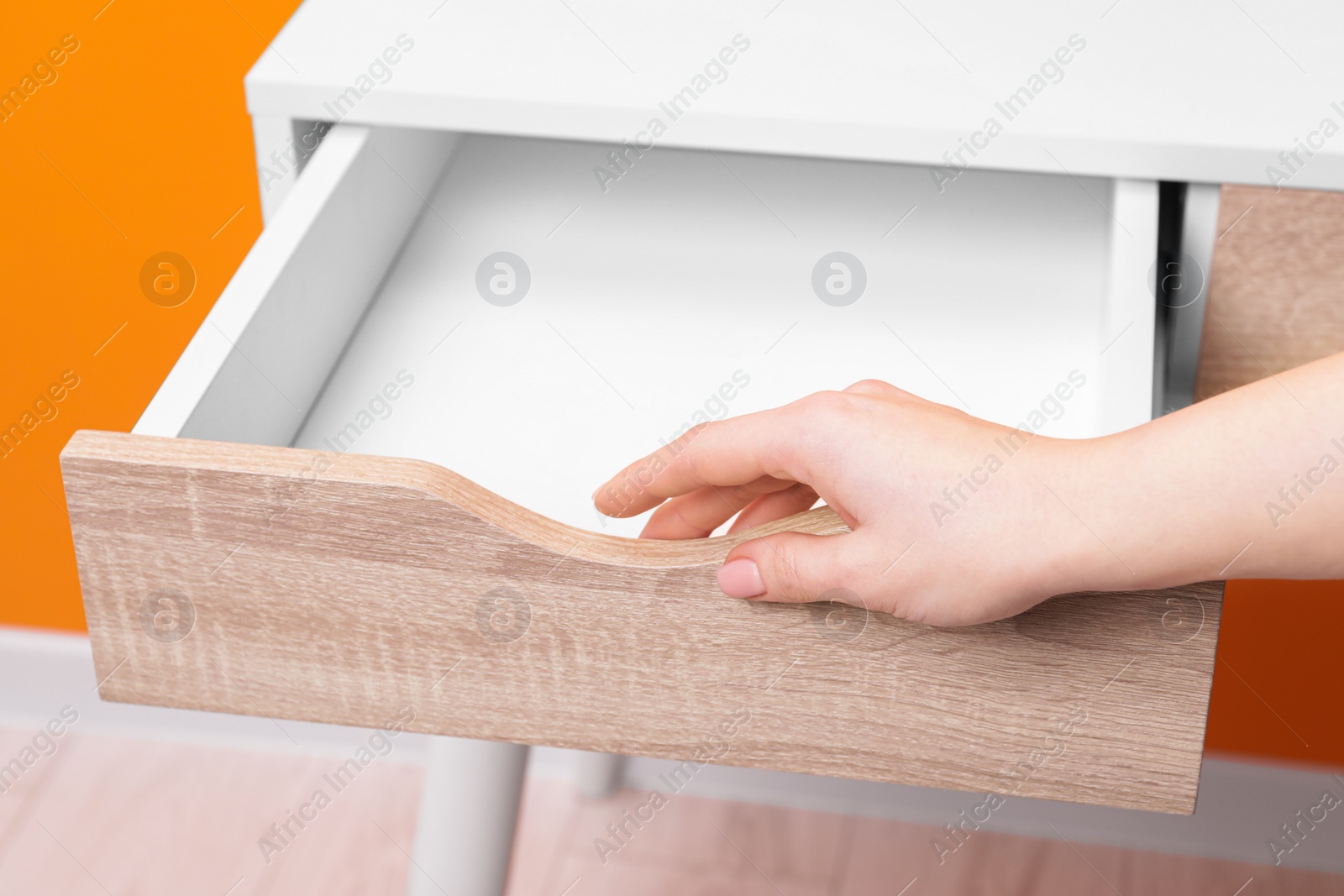 Photo of Woman opening empty desk drawer indoors, closeup