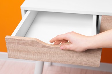 Photo of Woman opening empty desk drawer indoors, closeup