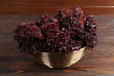 Photo of Bowl with fresh red coral lettuce on wooden table