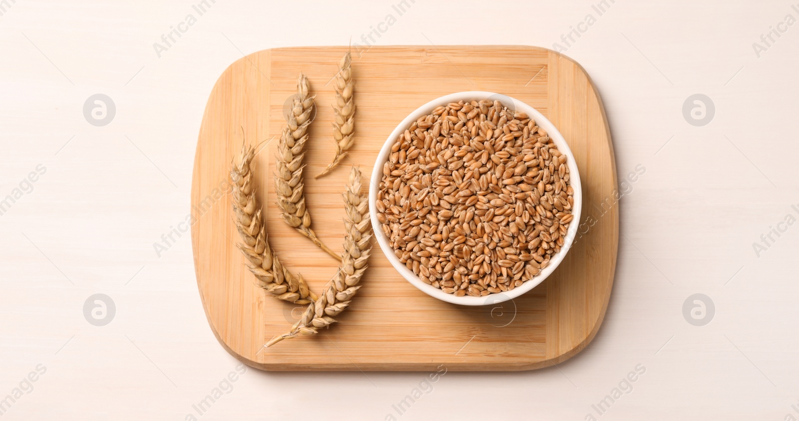 Photo of Wheat grains with spikelets on white table, top view