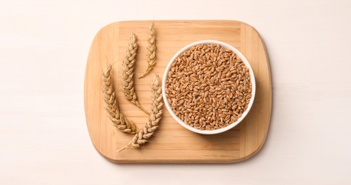 Wheat grains with spikelets on white table, top view