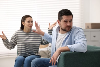 Photo of Tired husband stopping his wife indoors. Relationship problems