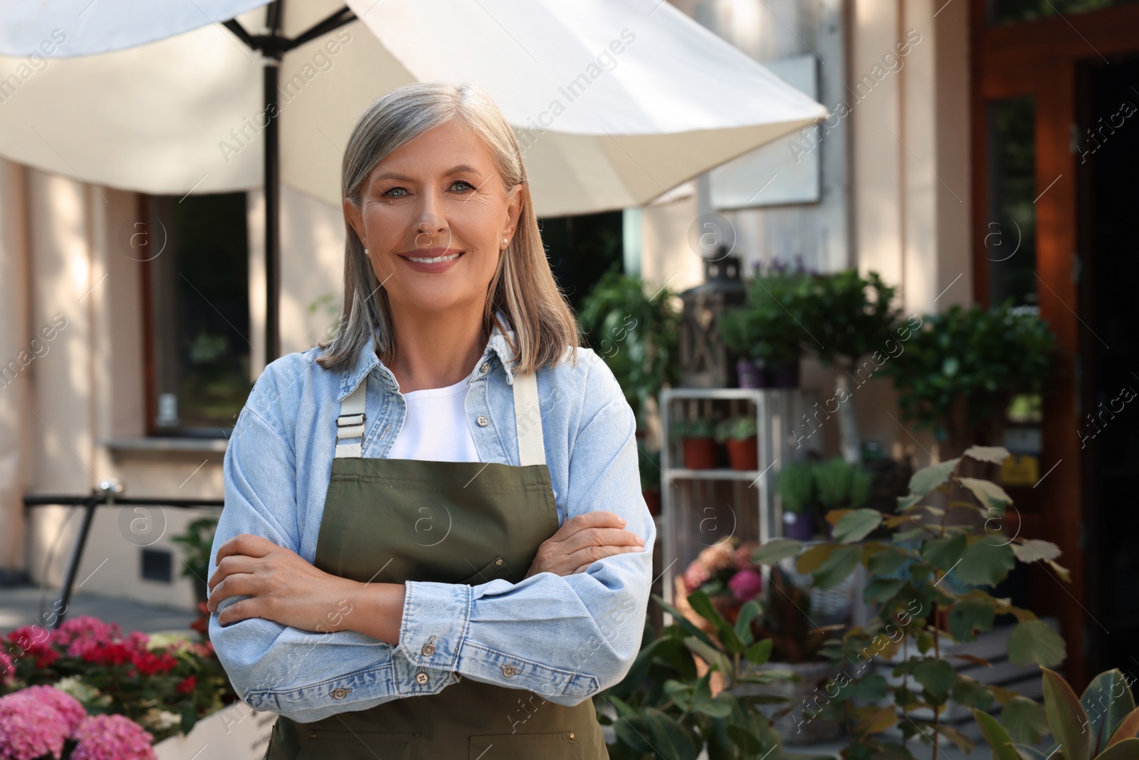 Photo of Portrait of happy business owner near her flower shop outdoors, space for text