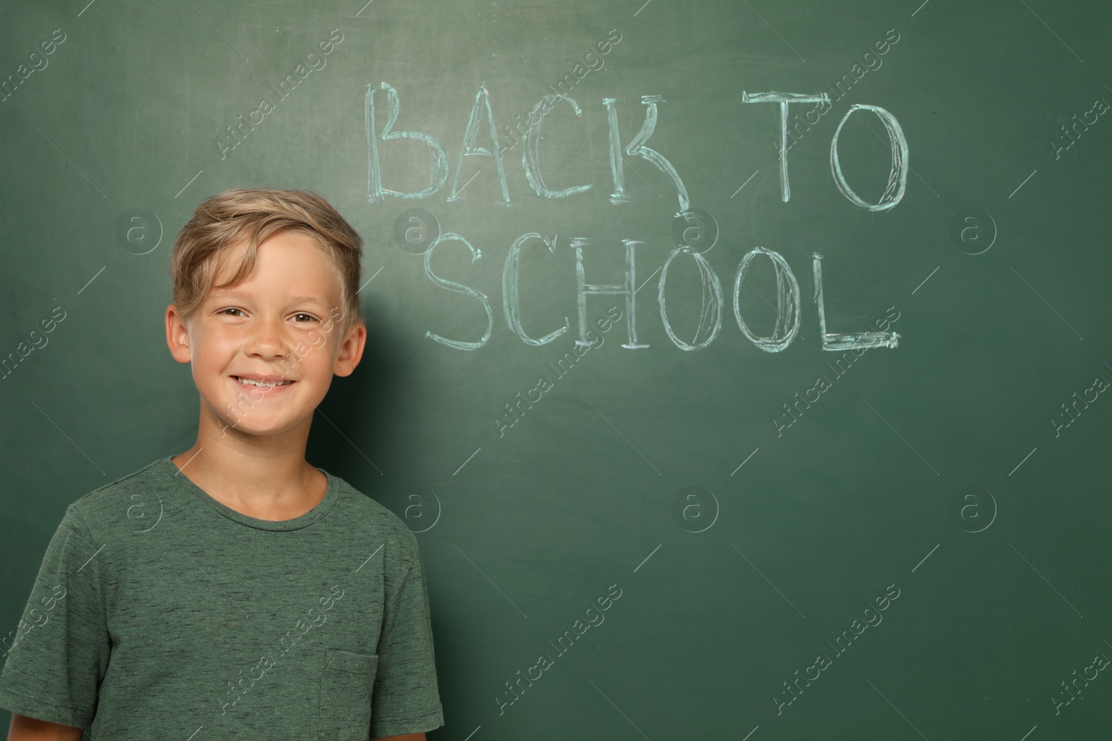 Photo of Little child near chalkboard with text BACK TO SCHOOL