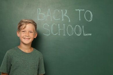 Little child near chalkboard with text BACK TO SCHOOL