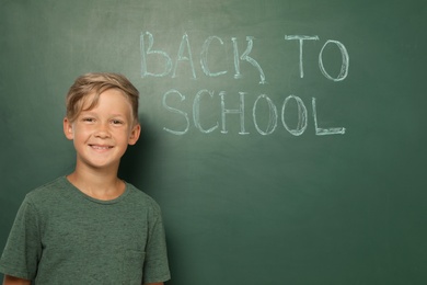 Photo of Little child near chalkboard with text BACK TO SCHOOL