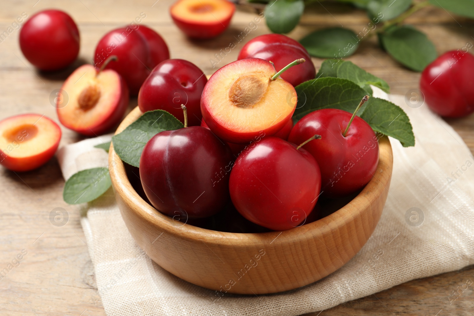 Photo of Delicious ripe cherry plums with leaves on wooden table