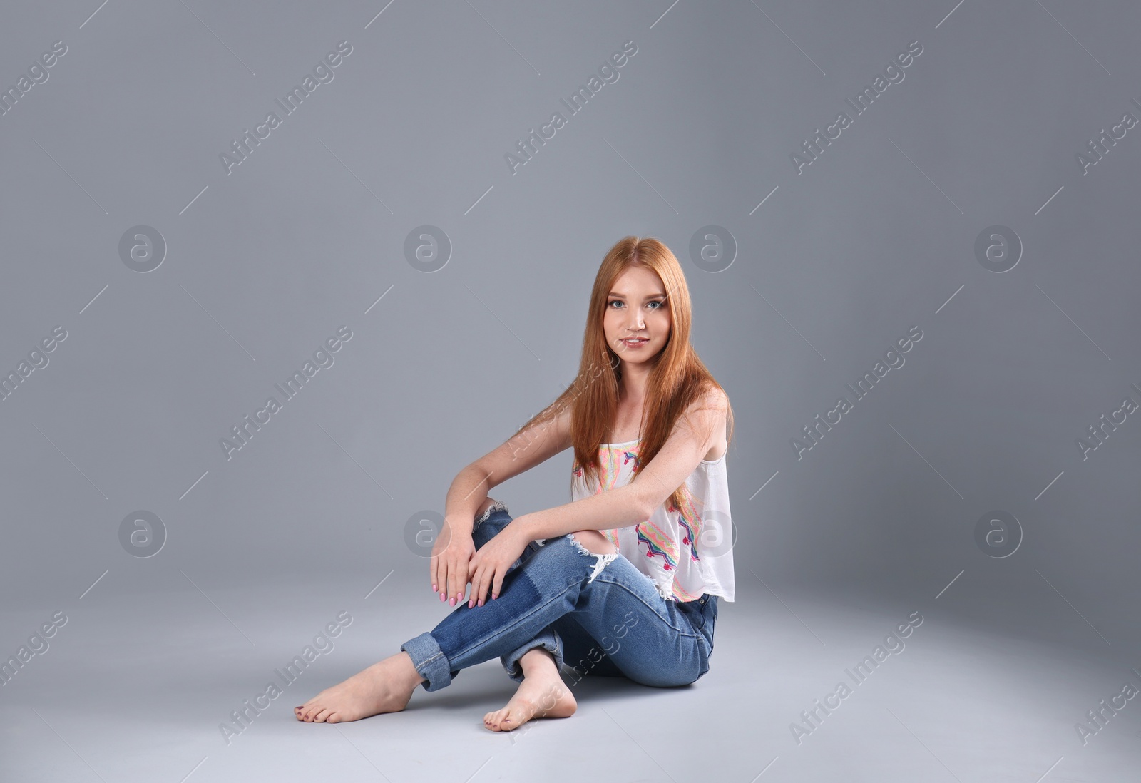 Photo of Young woman in stylish jeans on grey background