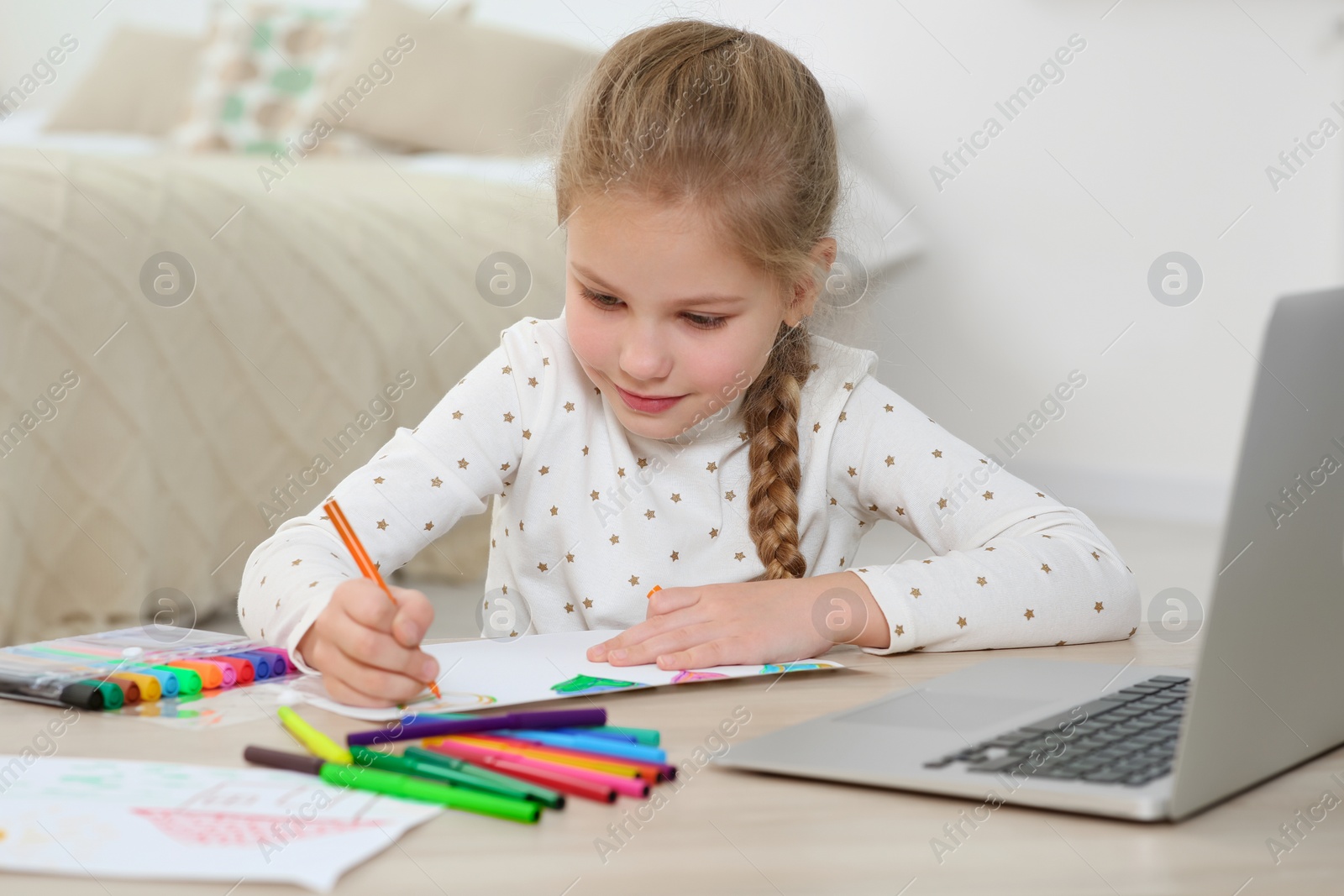 Photo of Little girl drawing with felt-tip pen following online course at home. Time for hobby