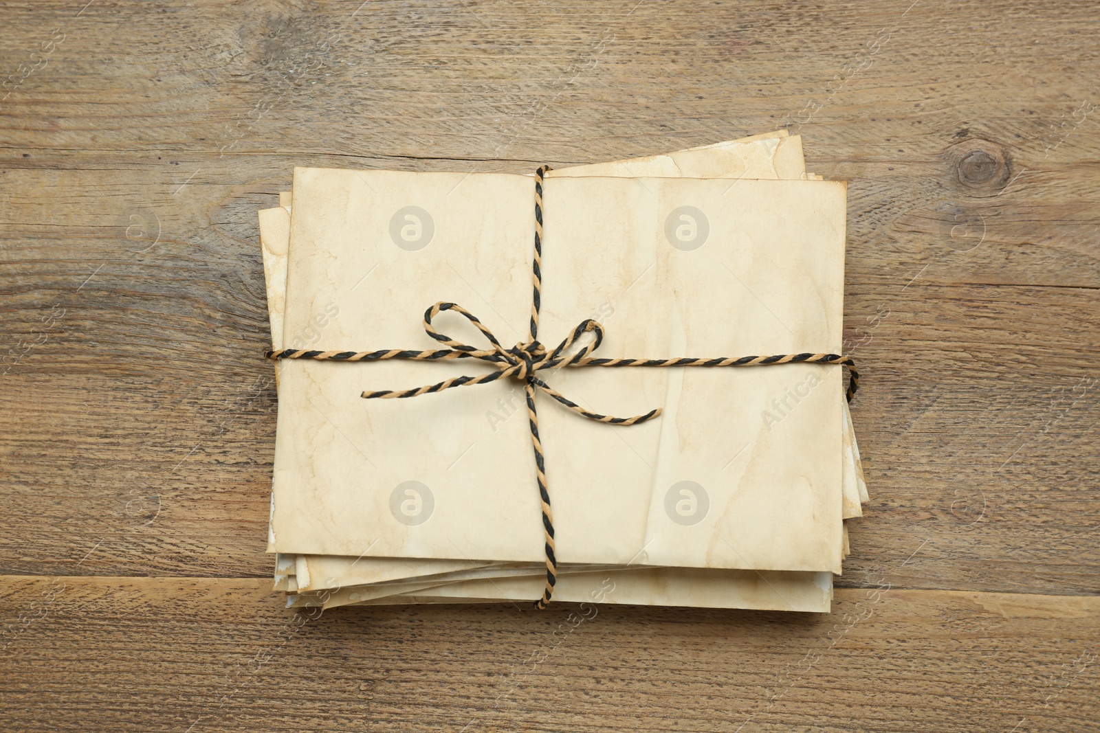 Photo of Stack of old letters tied with string on wooden table, top view