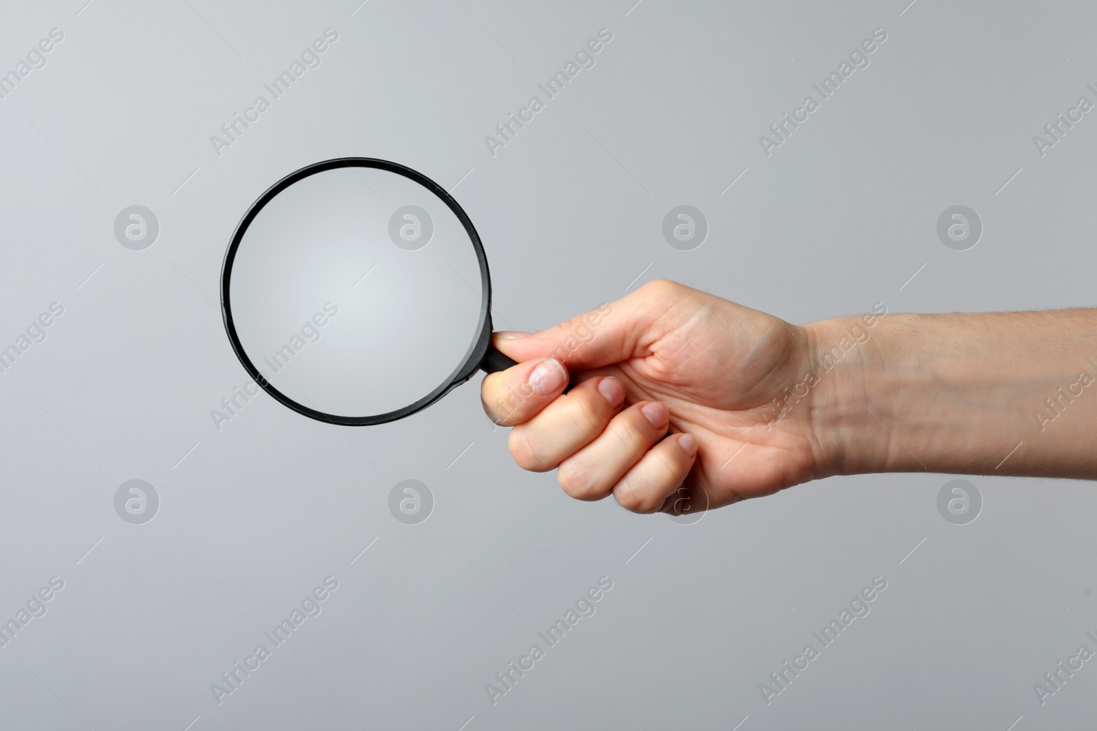 Photo of Woman holding magnifying glass on grey background, closeup. Find keywords concept