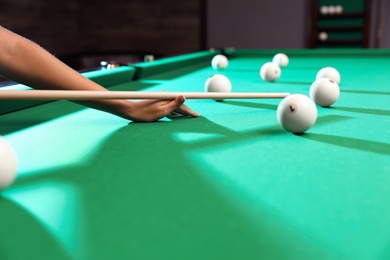 Young woman playing billiard indoors, closeup