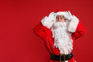 Photo of Merry Christmas. Surprised Santa Claus on red background, space for text