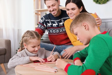 Photo of Cute children with their parents making beautiful Christmas greeting cards at home
