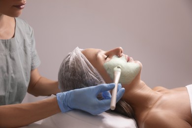 Cosmetologist applying mask on client's face in spa salon