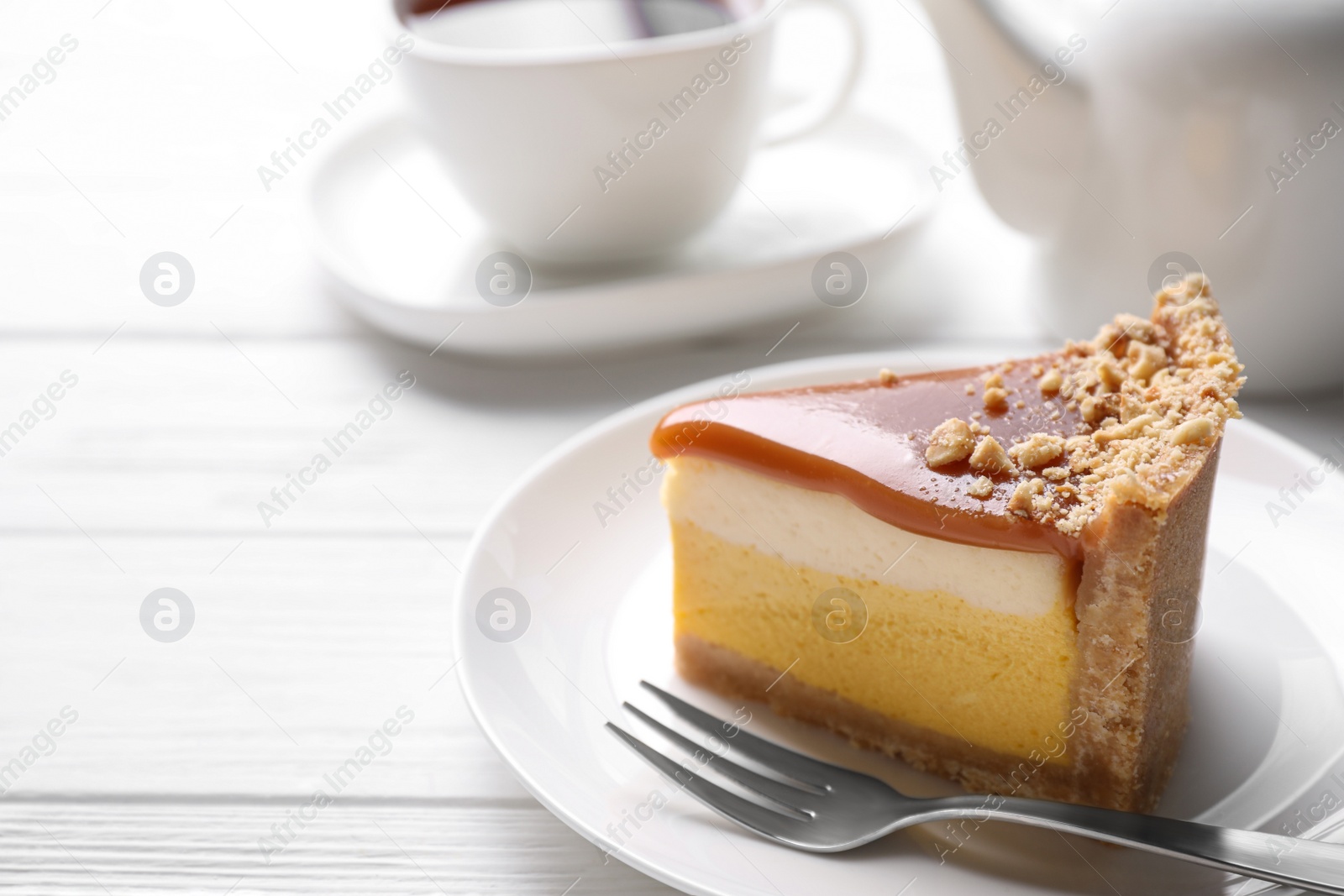 Photo of Piece of delicious cake with caramel served on white wooden table. Space for text