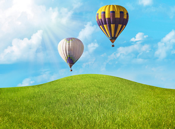 Image of Dream world. Hot air balloons in sky with clouds over green meadow