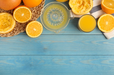 Freshly made juice, oranges and squeezer on blue wooden table, flat lay. Space for text