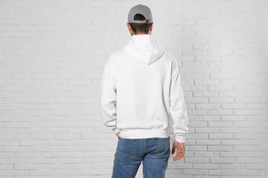 Photo of Young man in sweater at brick wall. Mock up for design