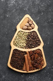 Photo of Different spices and nuts on dark gray textured table, top view