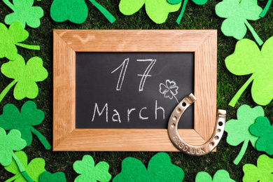 Photo of Flat lay composition with horseshoe and chalkboard on grass. St. Patrick's Day celebration