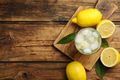 Cool freshly made lemonade and fruits on wooden table, flat lay. Space for text