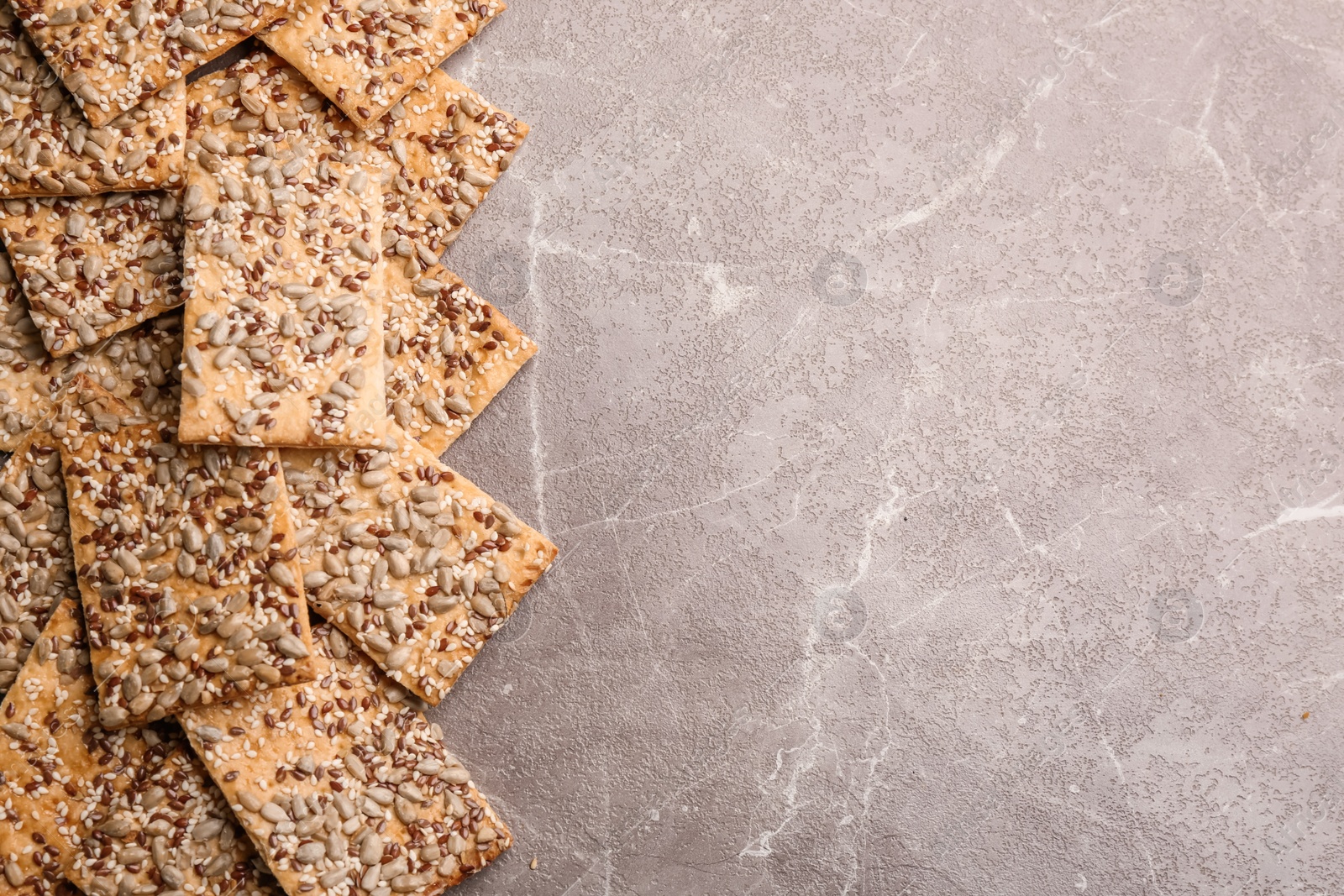 Photo of Many delicious crackers on grey table, flat lay. Space for text