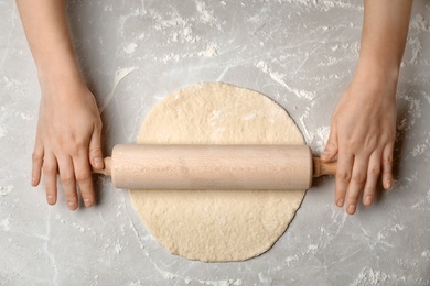 Photo of Young woman rolling dough at table, top view